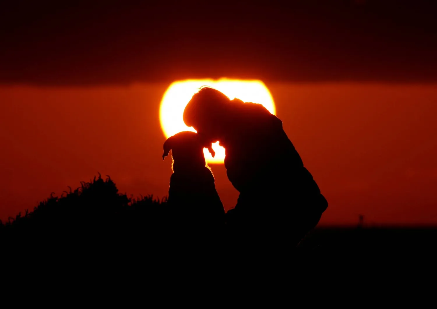 FILE PHOTO: A woman gives her dog a kiss as they watch the sunset at Anchor Bay outside Mellieha, Malta, January 26, 2018.  REUTERS/Darrin Zammit Lupi/File Photo