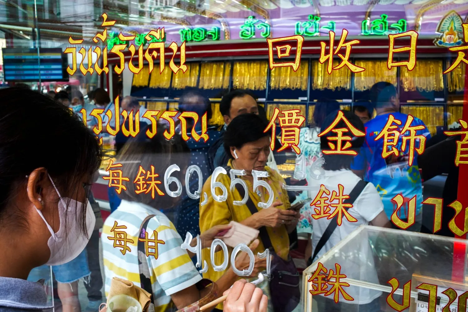 أحد الموظفين يقوم بتحديث أسعار الذهب بينما يصطف الزبائن داخل متجر للذهب في الحي الصيني ببانكوك (أ.ف.ب)