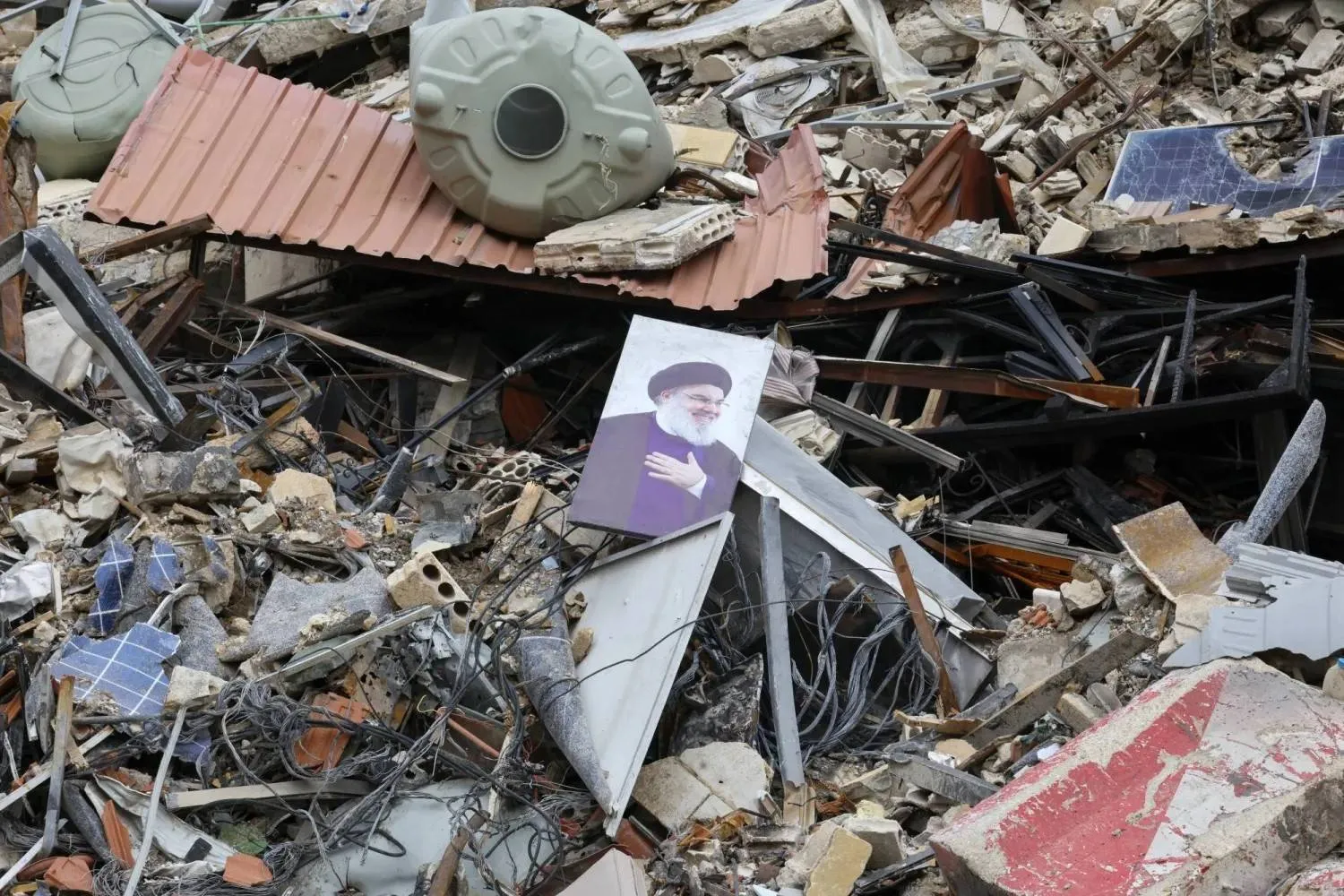 A photo of former Secretary-General of Hezbollah Hassan Nasrallah lies amid the rubble of an Al-Qard Al-Hassan Association building destroyed by an Israeli airstrike in Beirut’s southern suburbs (EPA) 