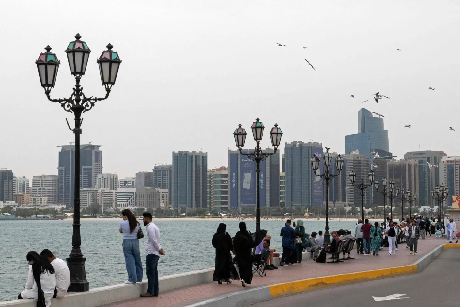 People walk along the corniche area in Abu Dhabi on March 20, 2026. (Photo by Ryan Lim / AFP)