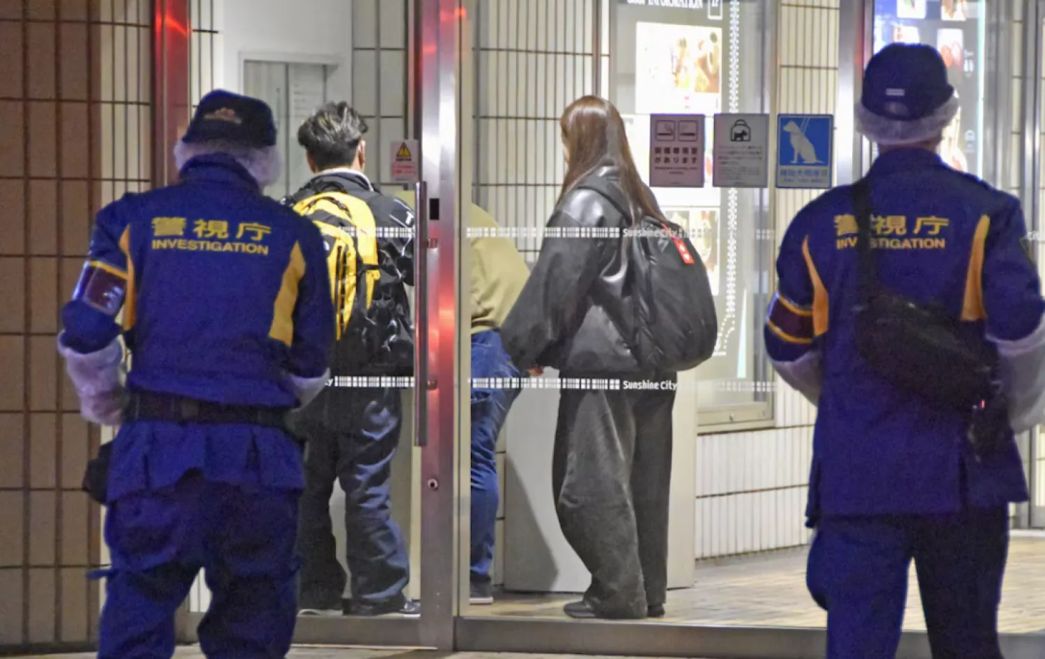 Police officers walk toward a commercial complex to investigate where a female employee at a Pokemon merchandise shop was stabbed to death at Ikebukuro district in Tokyo, Japan March 26, 2026, in this photo taken by Kyodo. Mandatory credit Kyodo/via REUTERS