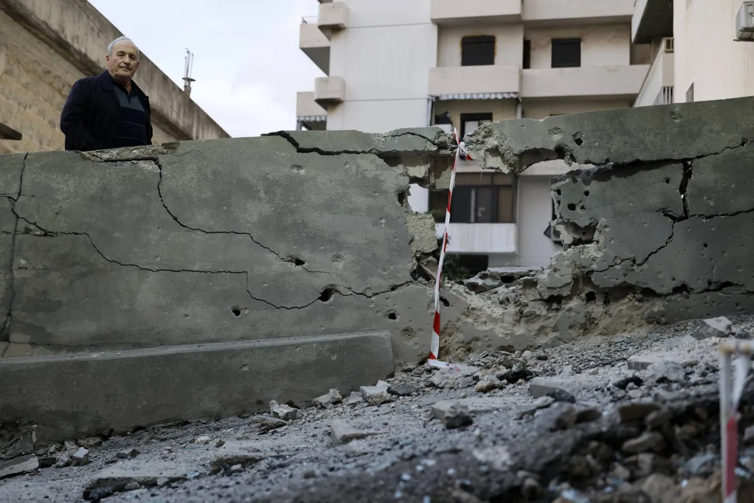 رجل يقف بجوار الموقع الذي سقطت فيه شظايا صاروخ تم اعتراضه بمنطقة حارة صخر بقضاء كسروان شمال بيروت 24 مارس 2026 (إ.ب.أ)