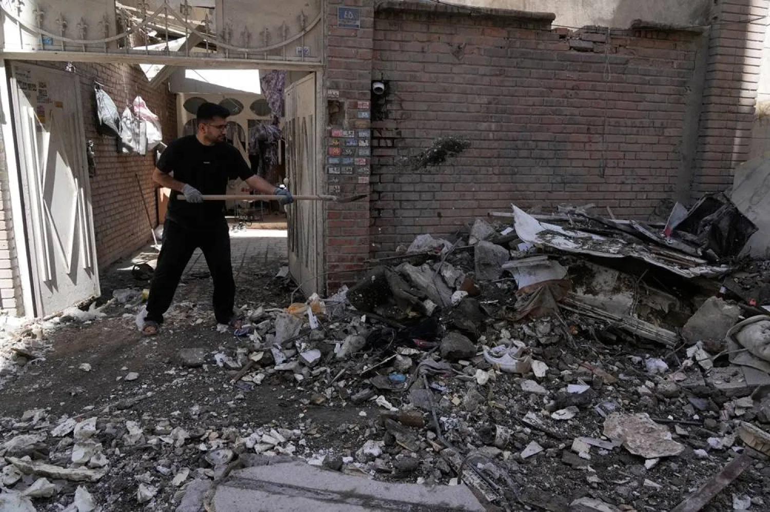  A man clears debris from a building damaged after a nearby residential building was hit in a US-Israeli strike in Tehran, Friday, March 27, 2026. (AP) 