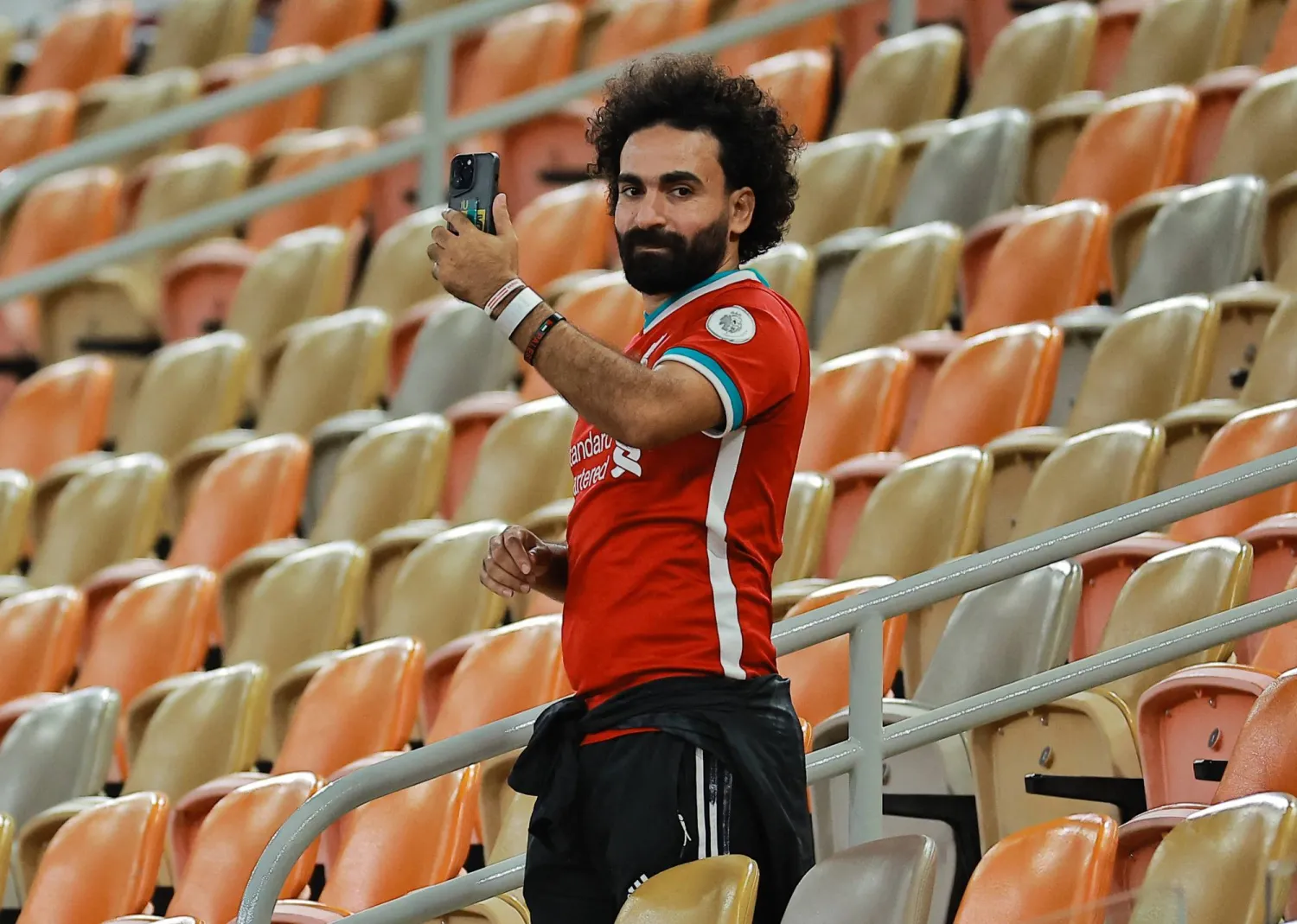 المشجع المصري شبيه النجم محمد صلاح يوثّق الحدث بهاتفه (رويترز)