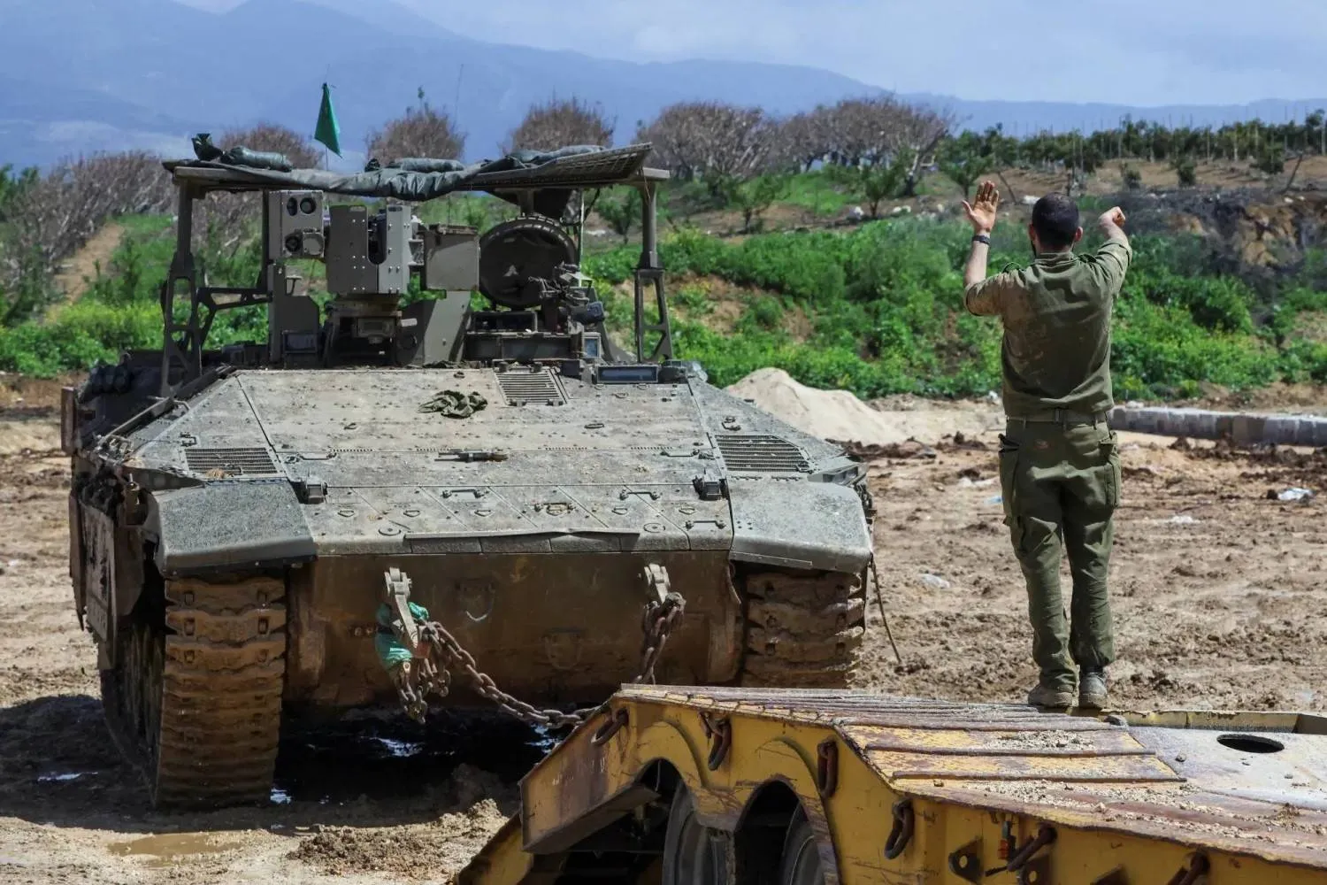 An Israeli soldier directs a tank near the Lebanese border (Reuters)