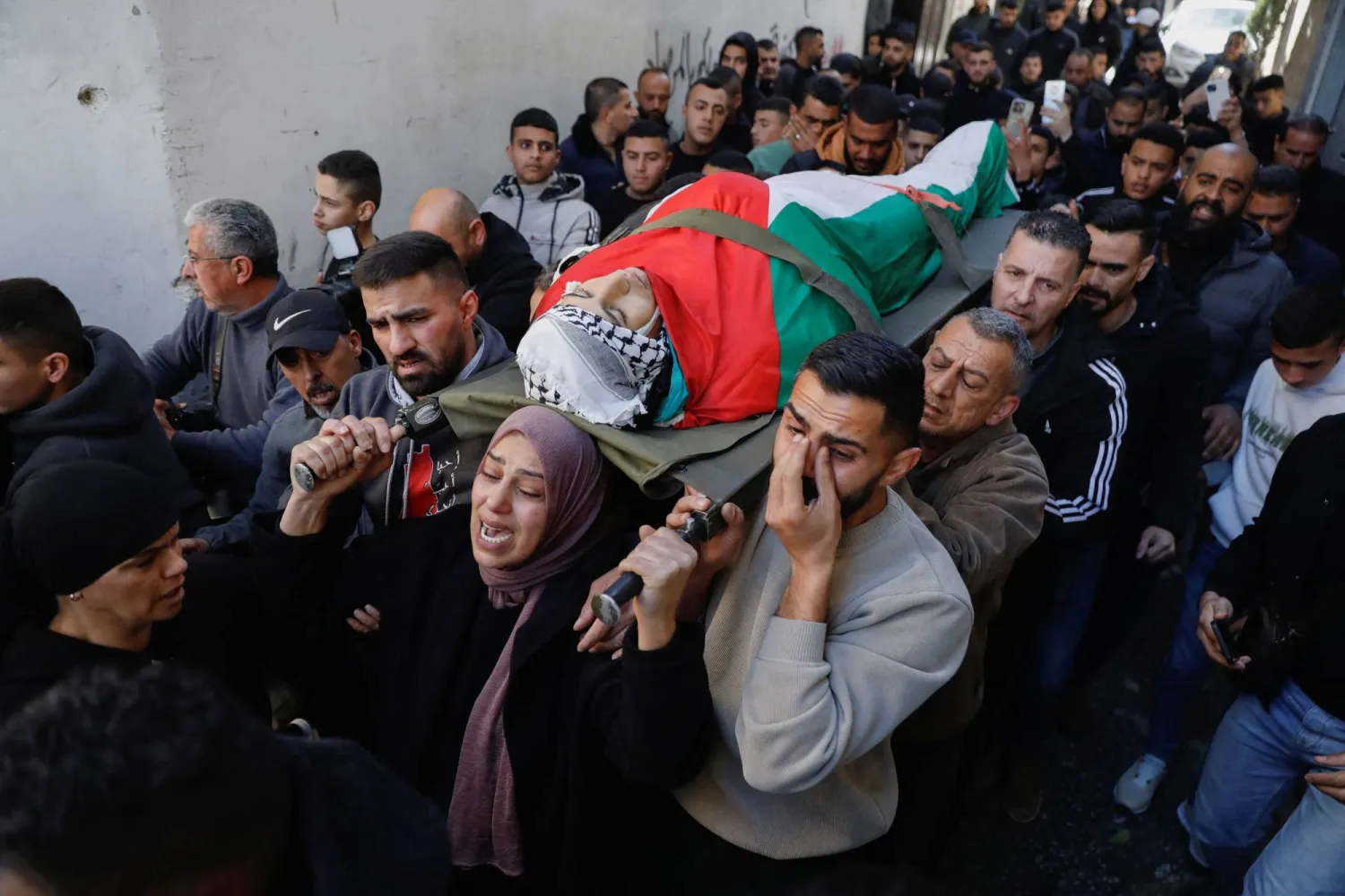 والدة الفتى الفلسطيني أدهم سيد صالح دهمان تقود جنازته في بيت لحم بالضفة الغربية المحتلة (رويترز)