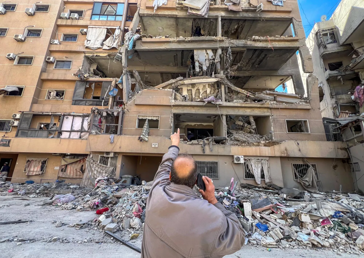 A man points at a building damaged by Israeli strikes in Beirut's southern suburbs, Lebanon, March 28, 2026. Picture taken with a mobile phone. REUTERS/Stringer