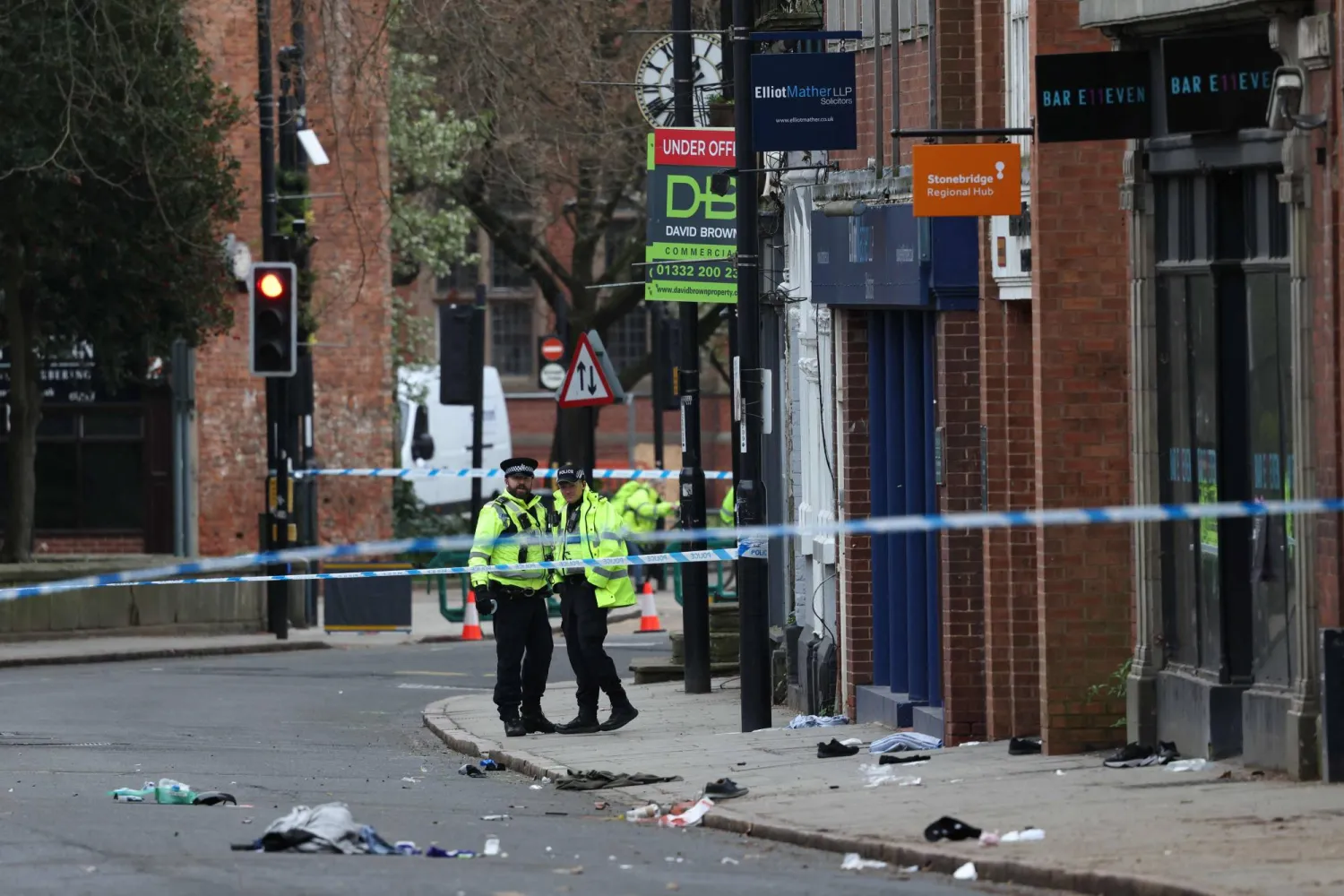 Police officers work near to a variety of personal items seen covering the road inside a cordon set up on Friar Gate in central Derby, central England on March 29, 2026, following an incident the night before where was vehicle has driven into pedestrians. (Photo by Darren Staples / AFP)
