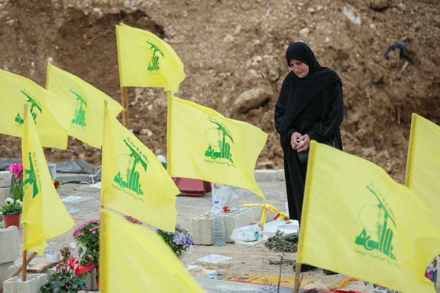 A woman stands amid Hezbollah flags on March 29, 2026, in the Choueifat area on the outskirts of Beirut during the funeral of journalists killed the previous day in an Israeli strike in south Lebanon. (AFP)