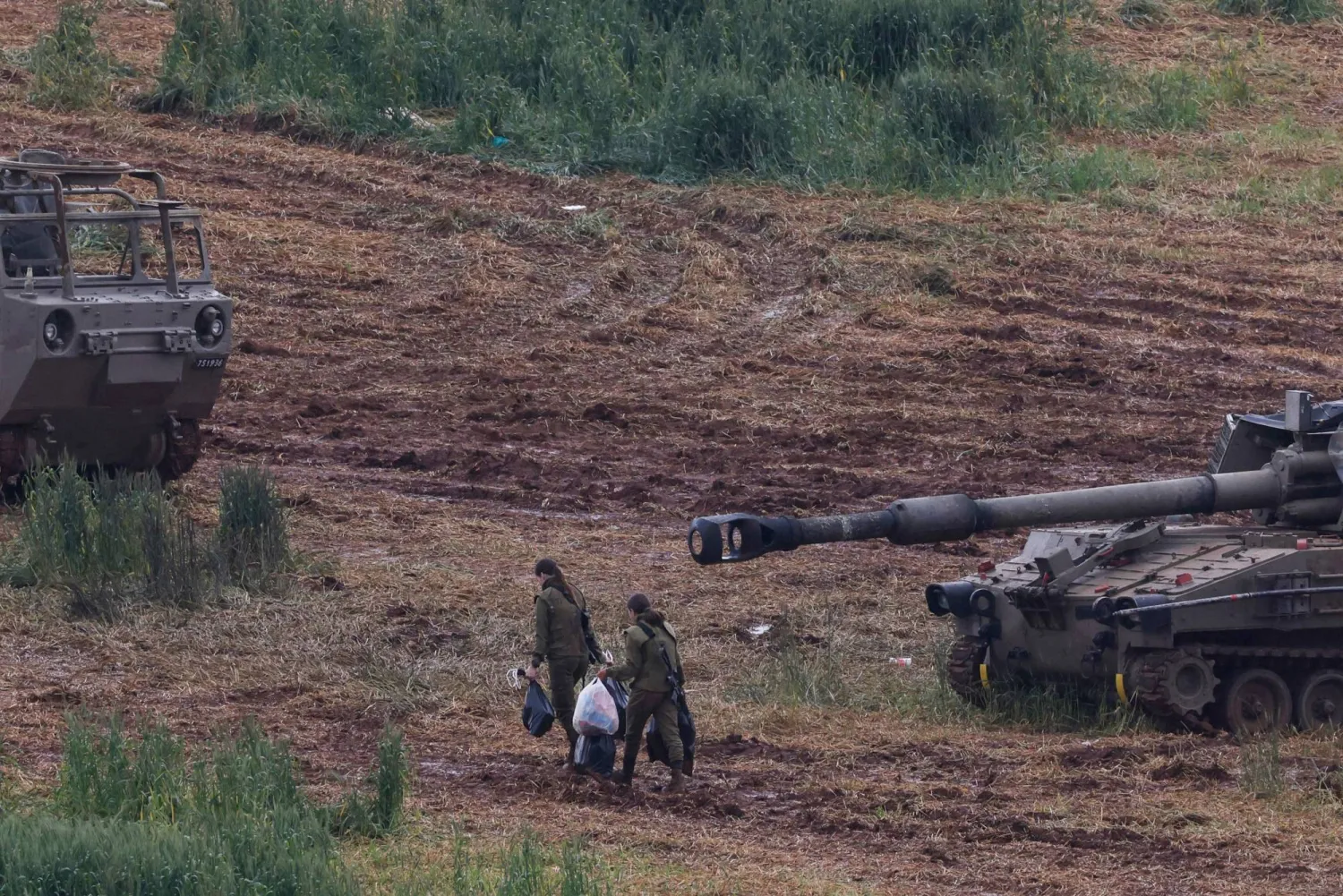 Israeli army soldiers walk next to a self-propelled Howitzer artillery gun positioned in the upper Galilee in northern Israel near the border with southern Lebanon on March 29, 2026. (AFP)