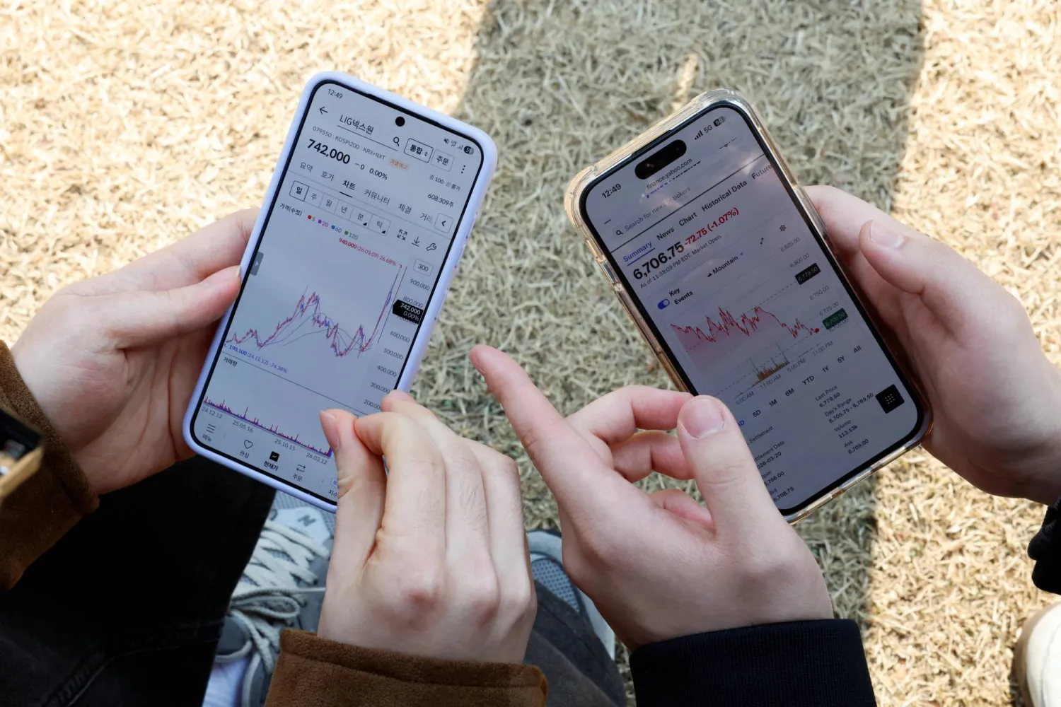 طالبان يتفقدان أسعار الأسهم على هاتفيهما في جامعة هانكوك بسيول (رويترز)