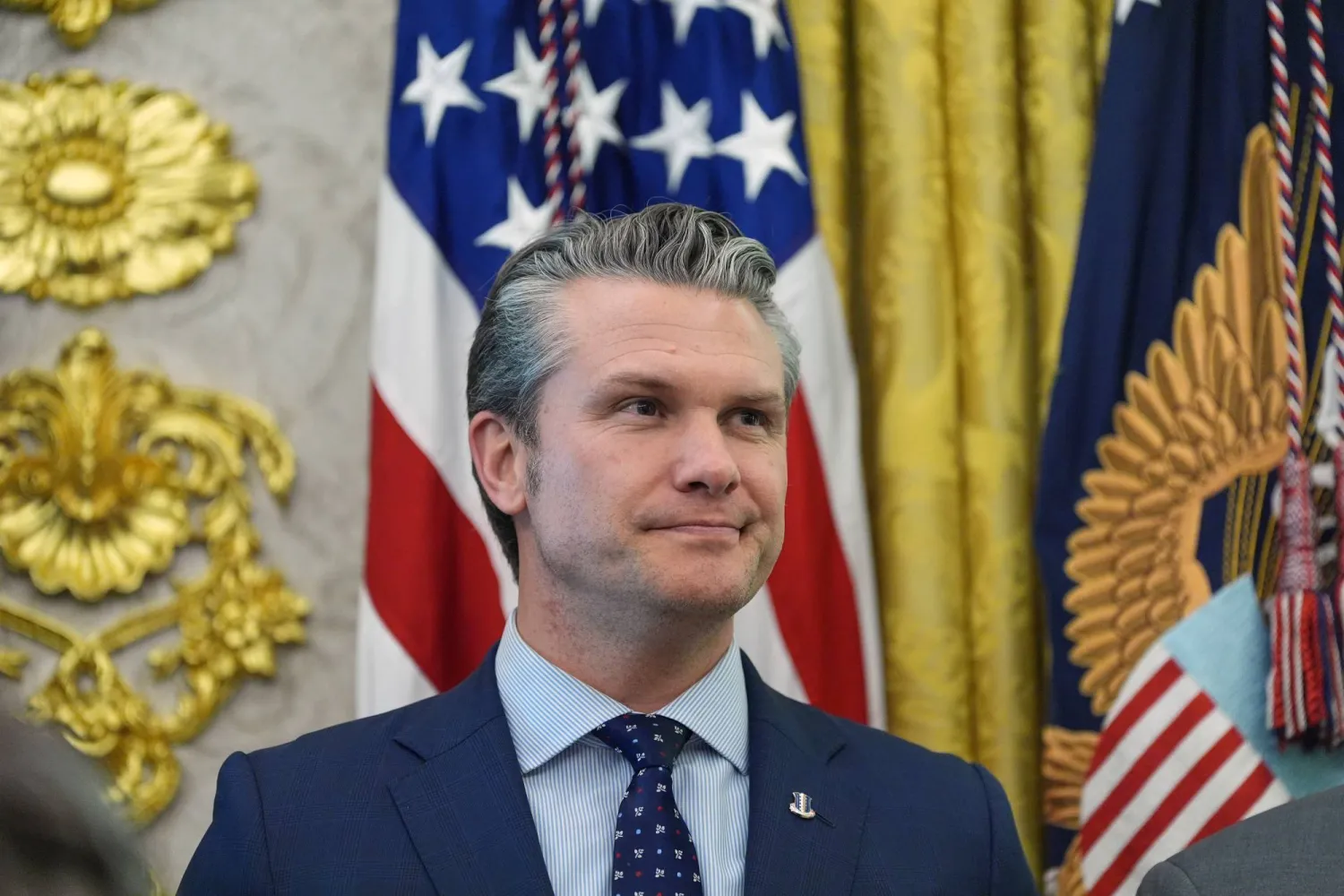 FILE - Defense Secretary Pete Hegseth listens as President Donald Trump speaks in the Oval Office of the White House, March 24, 2026, in Washington. (AP Photo/Alex Brandon, File)