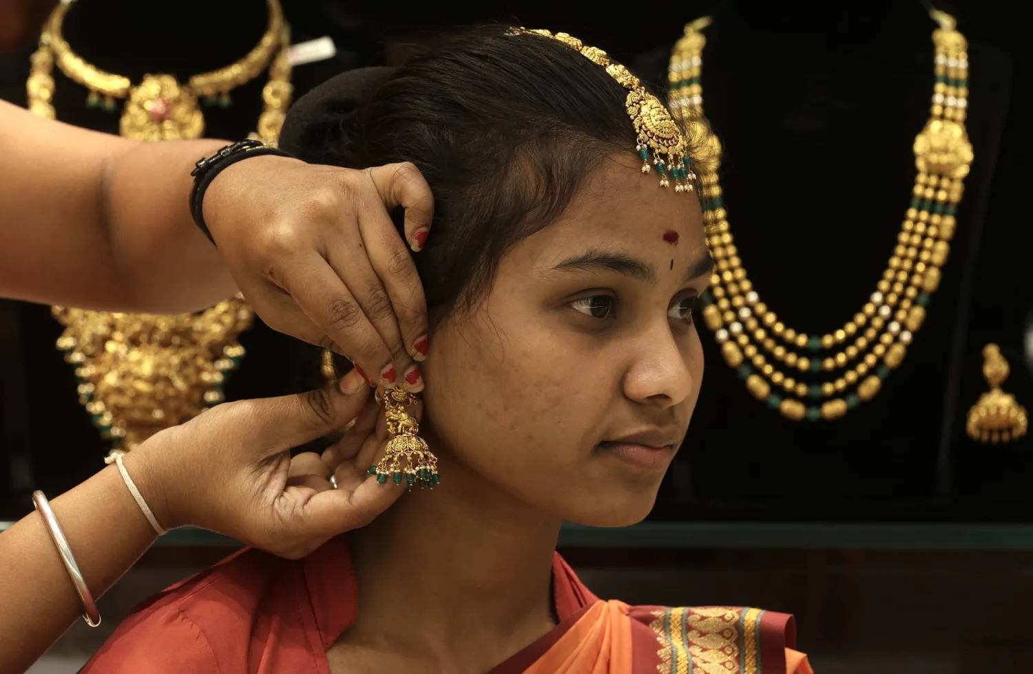 An Indian woman tries on gold ornaments at a jewelry shop in Bangalore (EPA)