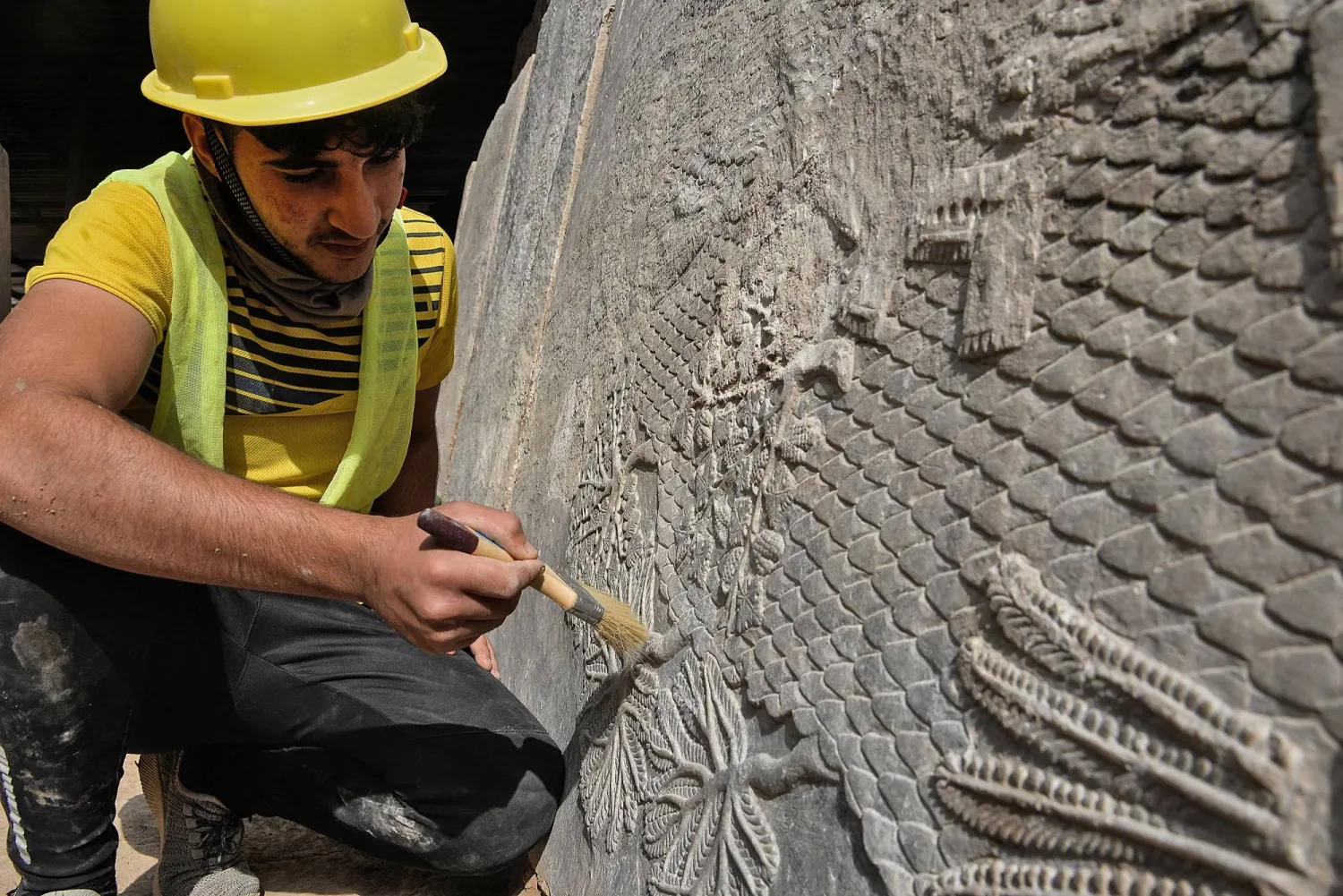 An Iraqi worker excavates a rock-carving relief recently found at the Mashki Gate, one of the monumental gates to the ancient Assyrian city of Nineveh, on the outskirts of what is today the northern Iraqi city of Mosul on October 19, 2022. (AFP)