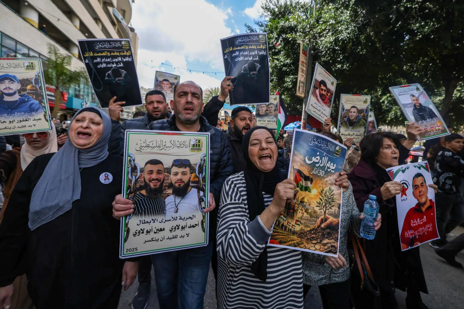 أقارب الأسرى الفلسطينيين يحملون لافتات ويهتفون بشعارات خلال مسيرة في مدينة نابلس بالضفة الغربية (أ.ف.ب)