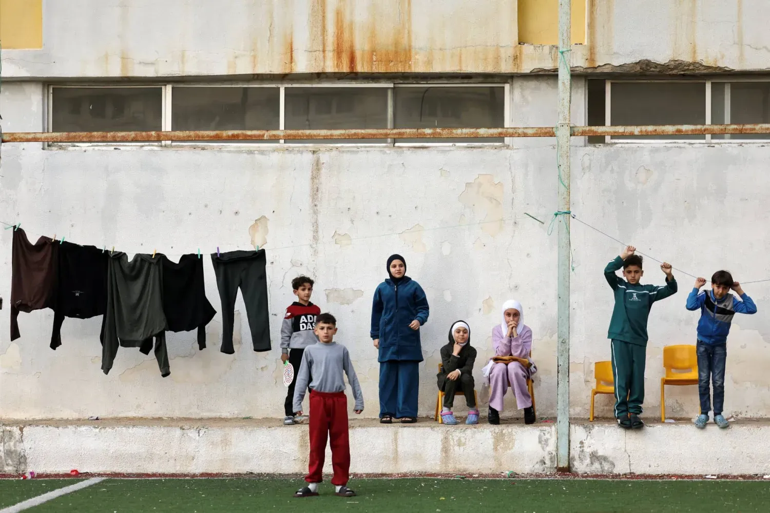 İsrail'in Lübnan'a yönelik saldırıları sırasında geçici sığınak olarak kullanılan ortaokulun bahçesinde bir grup yerinden edilmiş çocuk (Reuters)