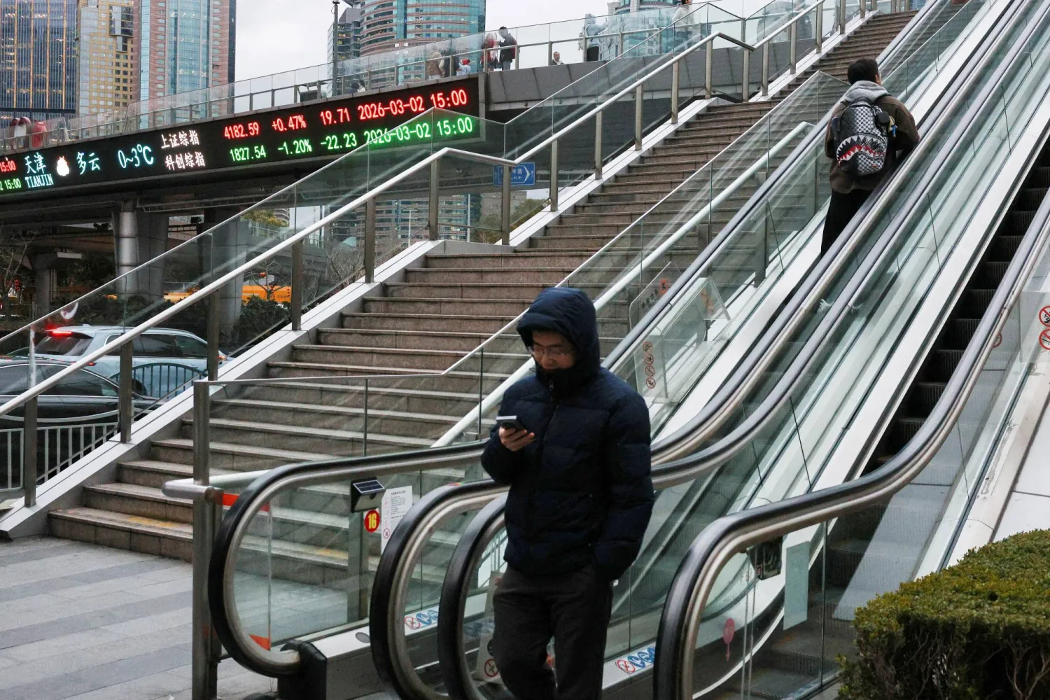 شاشة إلكترونية تعرض حركة الأسهم على جسر للمشاة في مدينة شنغهاي الصينية (رويترز)