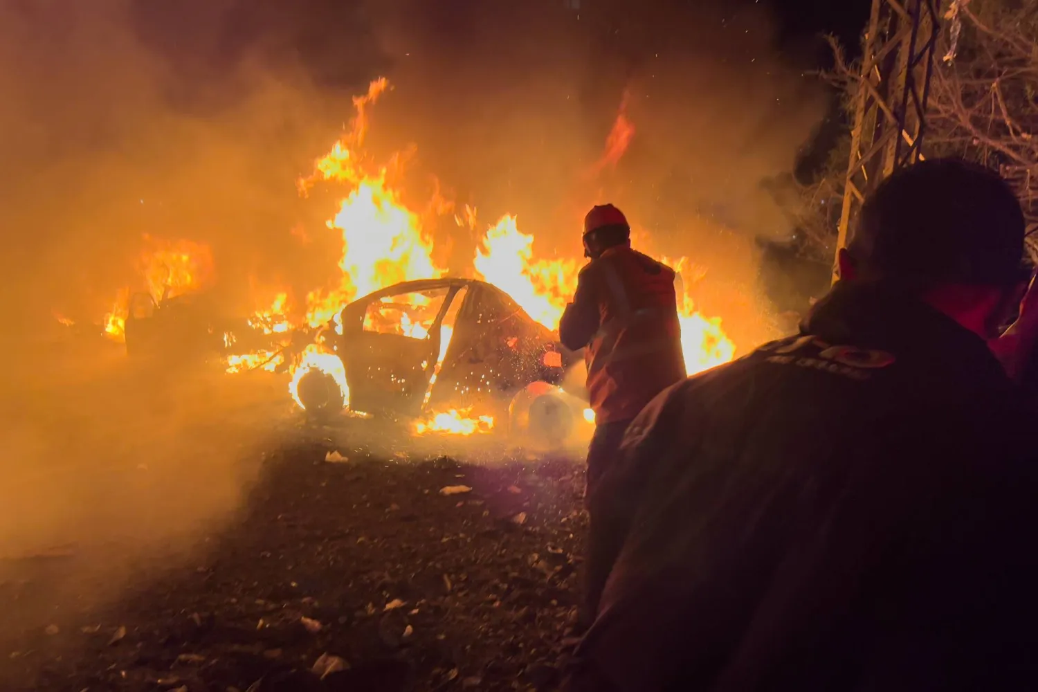 عمال إنقاذ يتفقدون موقع الضربة الإسرائيلية وسط احتراق عدد من السيارات ببيروت (أ.ب)