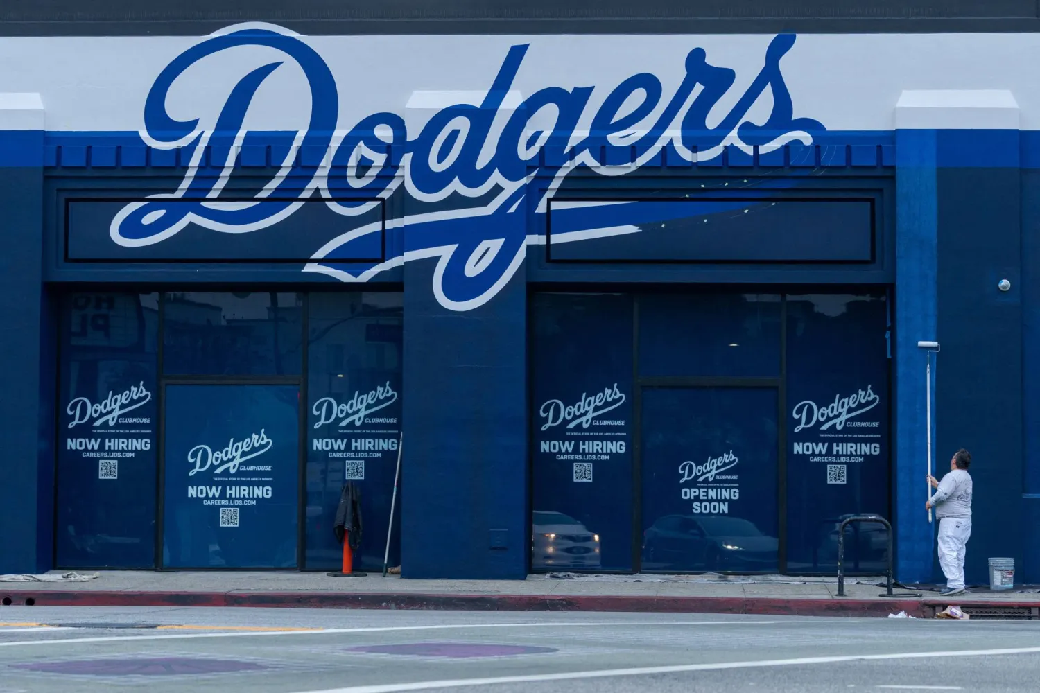 عامل يدهن الجدران الخارجية لمبنى يعرض وظائف لدى فريق «لوس أنجليس دودجرز» وسط مدينة لوس أنجليس (رويترز)