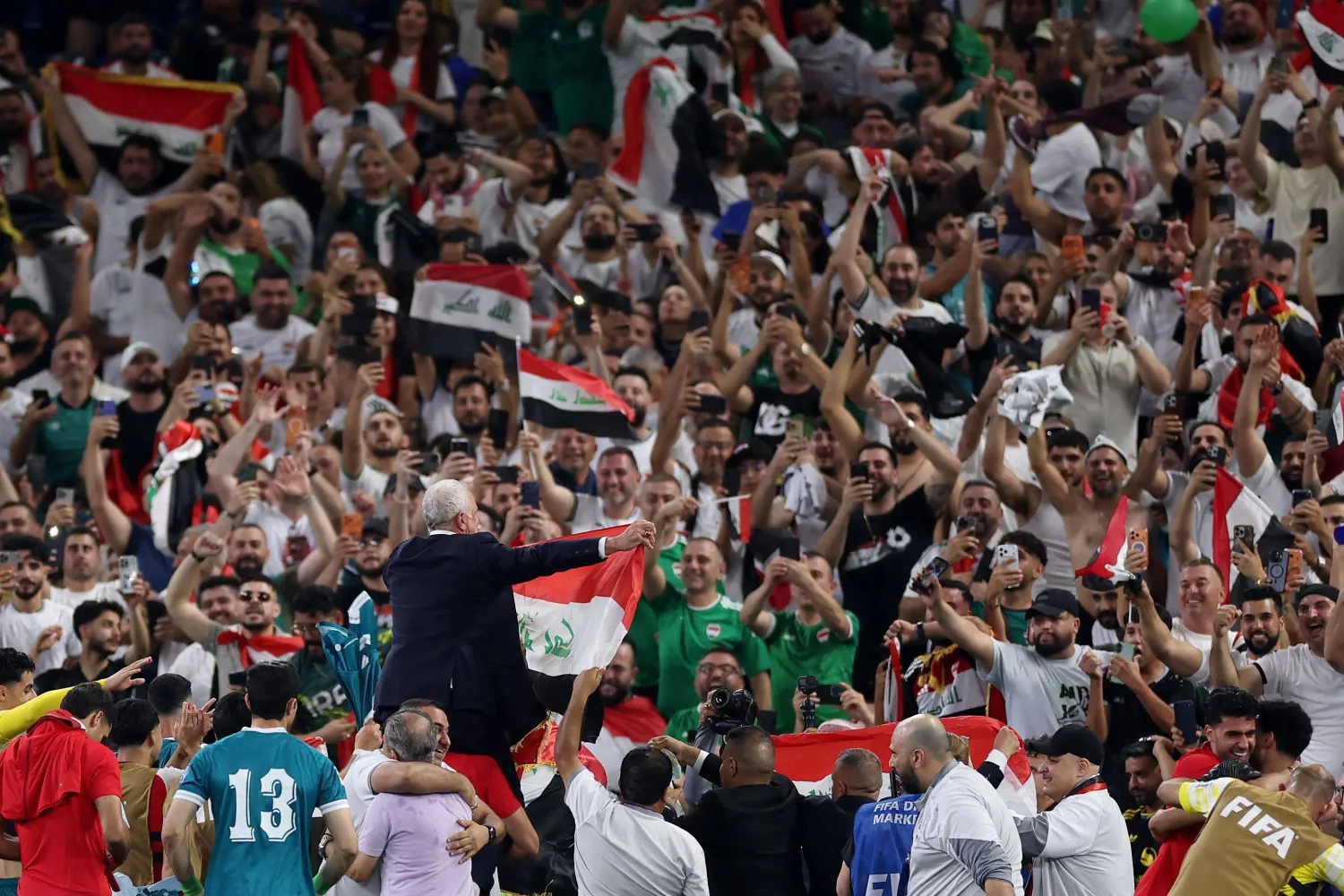 لاعبو العراق يحملون مدربهم على الأعناق بعد نهاية المباراة (أ.ف.ب)