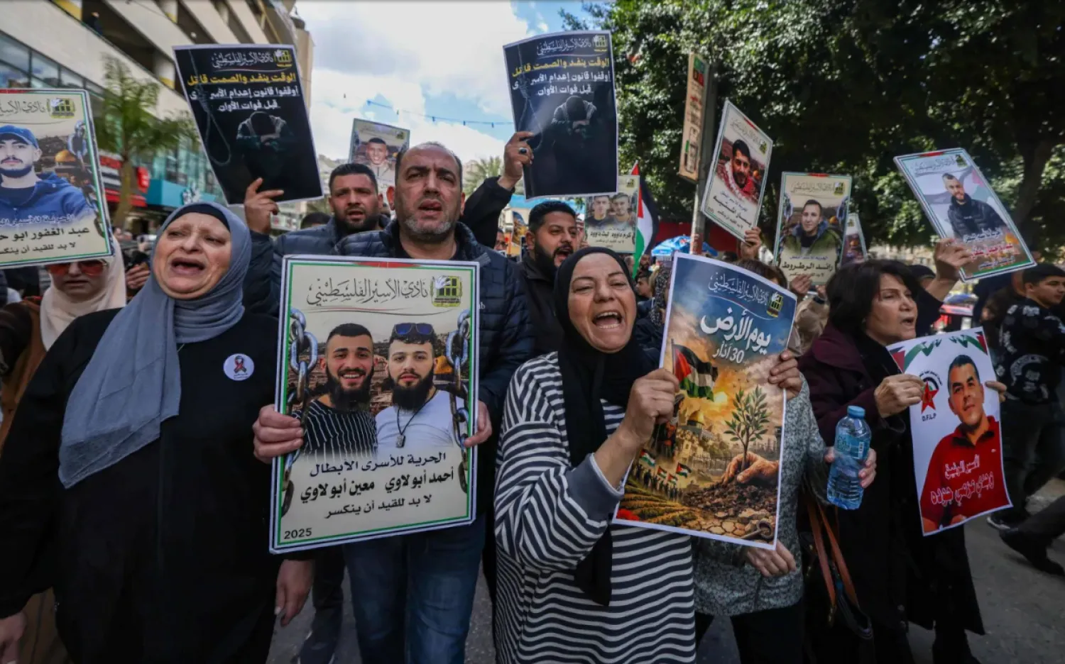 أقارب الأسرى الفلسطينيين يحملون لافتات ويهتفون بشعارات خلال مسيرة في مدينة نابلس بالضفة الغربية (أ.ف.ب)