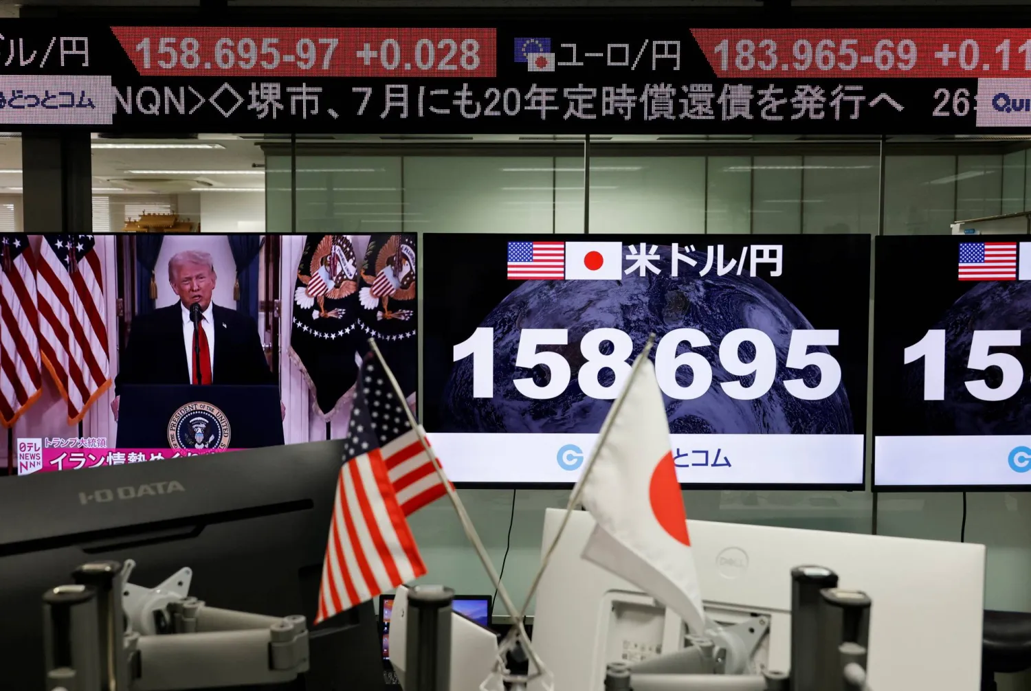شاشة تعرض خطاب ترمب بجوار شاشات تعرض سعر صرف الين مقابل الدولار في غرفة تداول بطوكيو (رويترز)