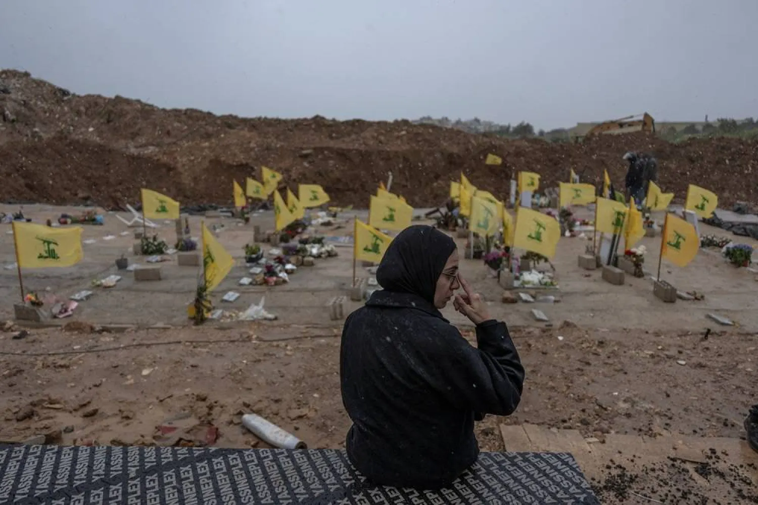 A woman sits in a cemetery before the funeral of Lebanese journalists, Al Manar reporter Ali Shoeib, Al Mayadeen reporter Fatima Ftouni and cameraman Mohammed Ftouni, who were killed by a targeted Israeli strike, amid escalating hostilities between Israel and Hezbollah, as the US-Israeli conflict with Iran continues, in Choueifat, Lebanon, March 29, 2026. (Reuters) 