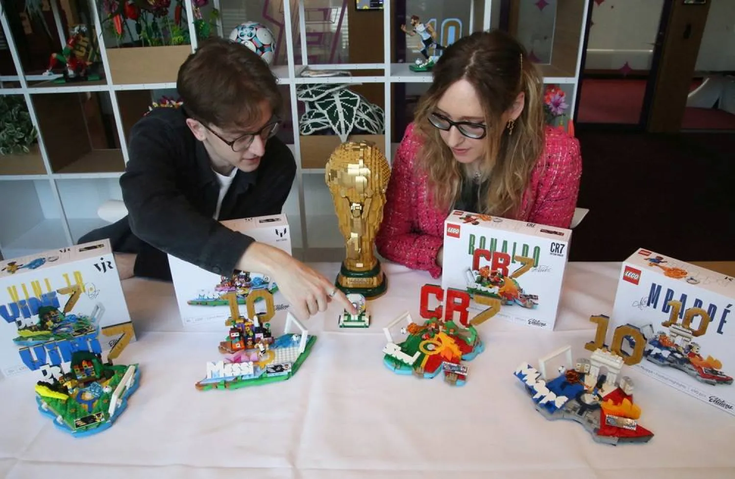 LEGO Design Master Beatrice Amoretti and model designer Freddy Charters sit next to a display of the LEGO Editions sets of footballers Vinicius (Vini) Jr, Lionel Messi, Cristiano Ronaldo, and Kylian Mbappe in Billund, Denmark, March 27, 2026. (Reuters) 