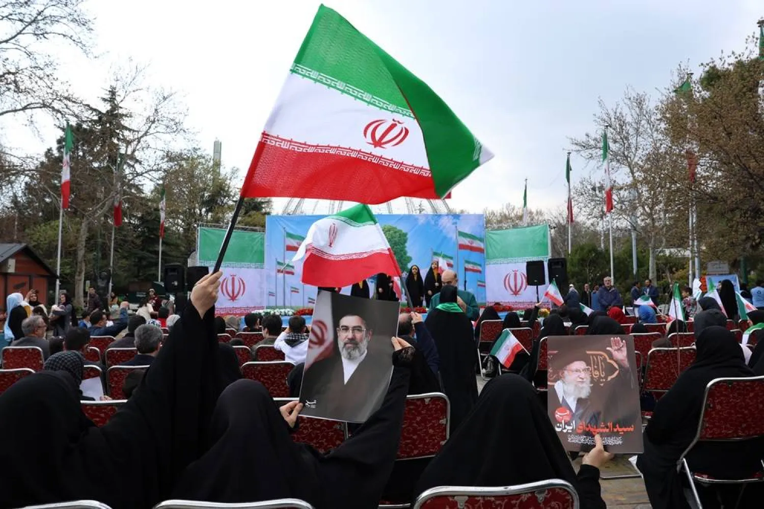 Iranian women clad in black chadors wave national flags and hold posters of Iranian Supreme Leader Mojtaba Khamenei (C) and of his late father, former Iranian Supreme Leader Ali Khamenei (R), during the annual Nature Day festival in Tehran, Iran, 02 April 2026. (EPA)