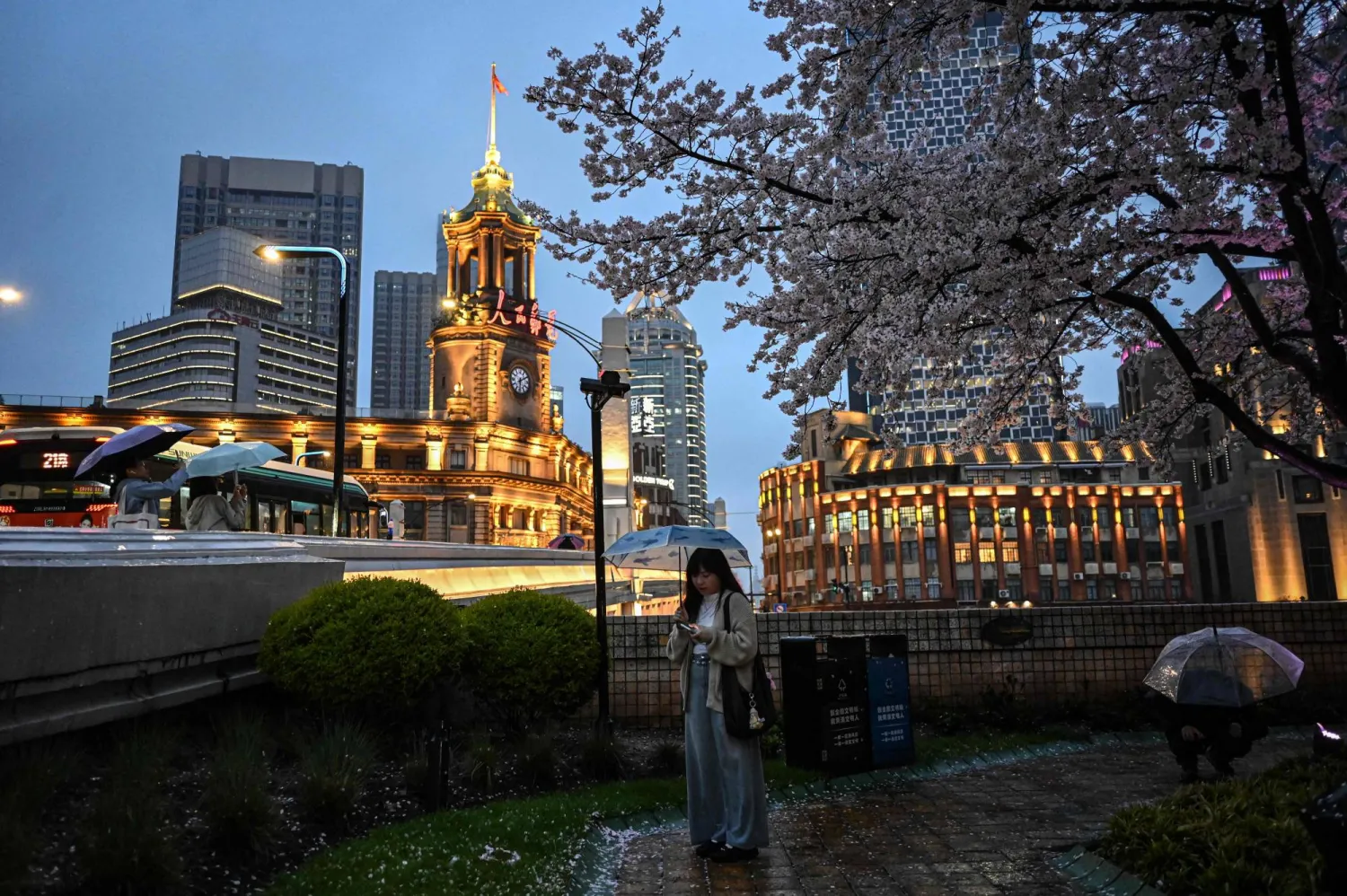 سيدة تسير تحت الأمطار في مدينة شنغهاي الصينية (أ.ف.ب)