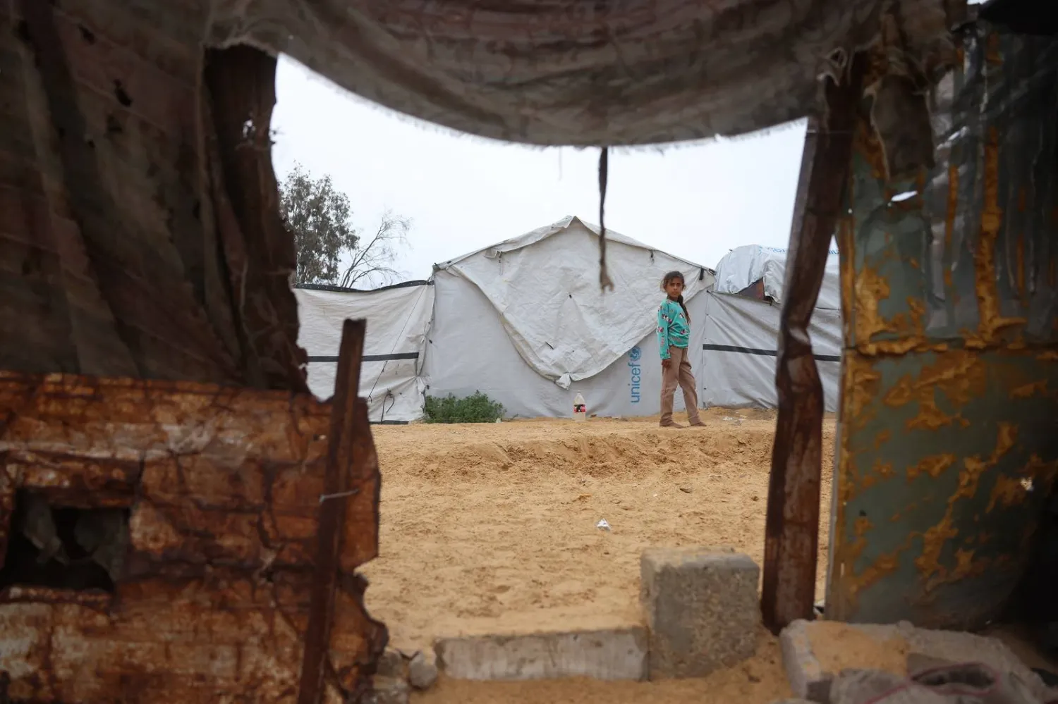 فتاة تقف بجوار خيمة في مخيم مؤقت للنازحين الفلسطينيين في منطقة نهر البارد في خان يونس جنوب قطاع غزة (أ.ف.ب)