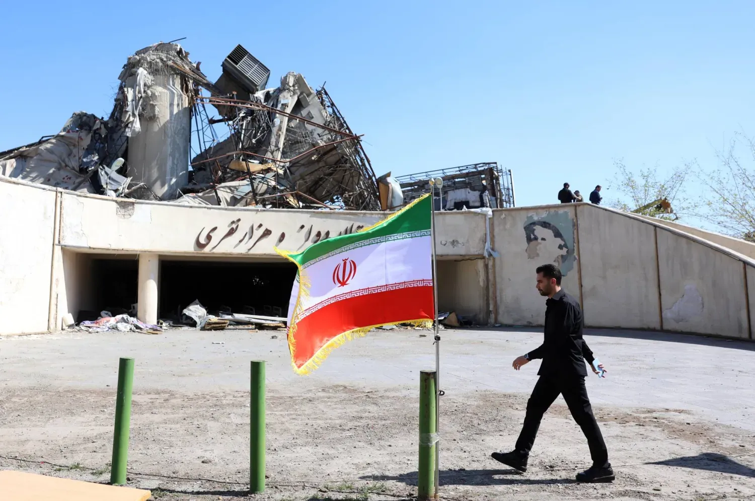 Tahran'da İran bayrağının önünden geçen bir kişi (EPA)