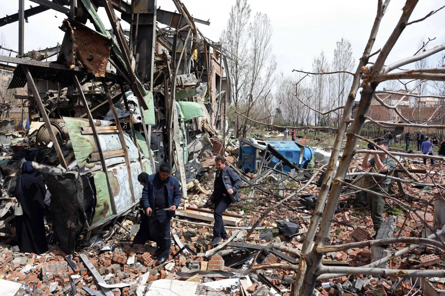 Officials and media representatives gather around the damaged building of the Shahid Beheshti University following a strike, in Tehran on April 4, 2026. (AFP)