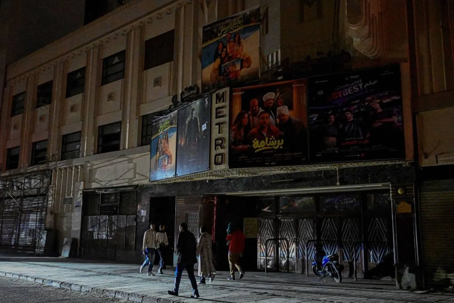 People walk past a closed cinema as shops close early under a government-ordered curfew aimed at reducing energy costs in downtown Cairo on April 2, 2026. (AFP)