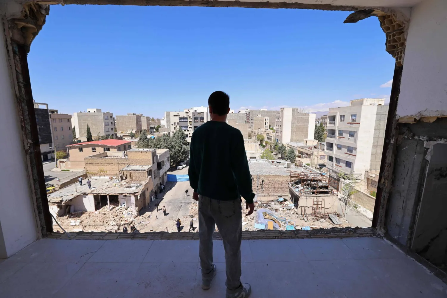 A man looks at the residential buildings that were damaged by recent strikes at Vahdat town in Karaj, southwest of Tehran on April 3, 2026. (AFP)