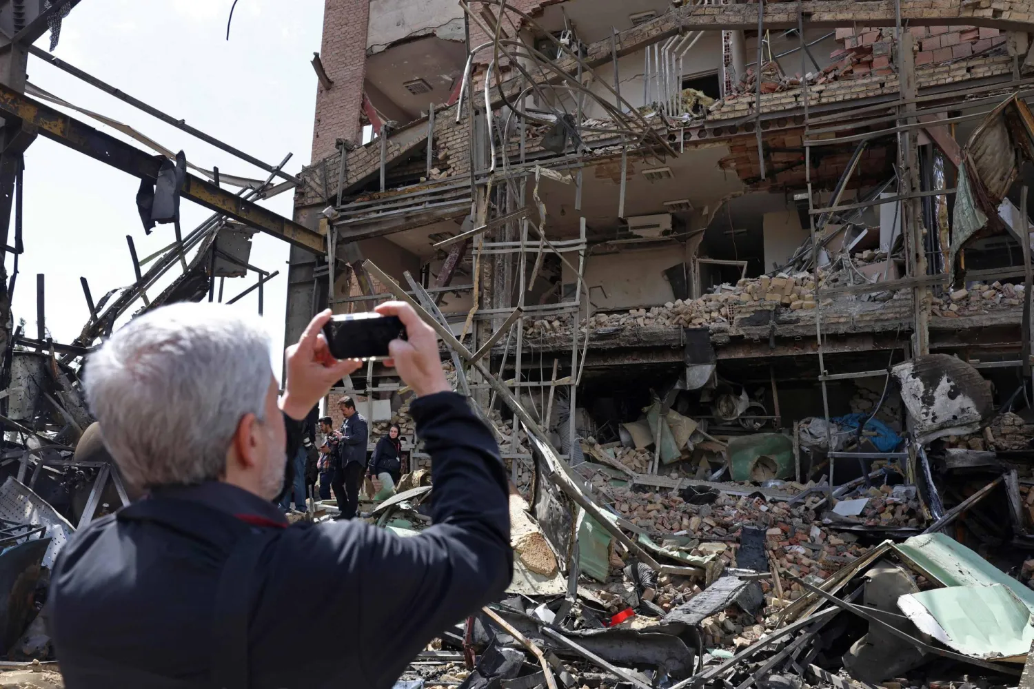 رجل يلتقط صوراً لمبنى جامعة شهيد بهشتي المتضرر عقب غارة جوية في طهران (ا.ف.ب)