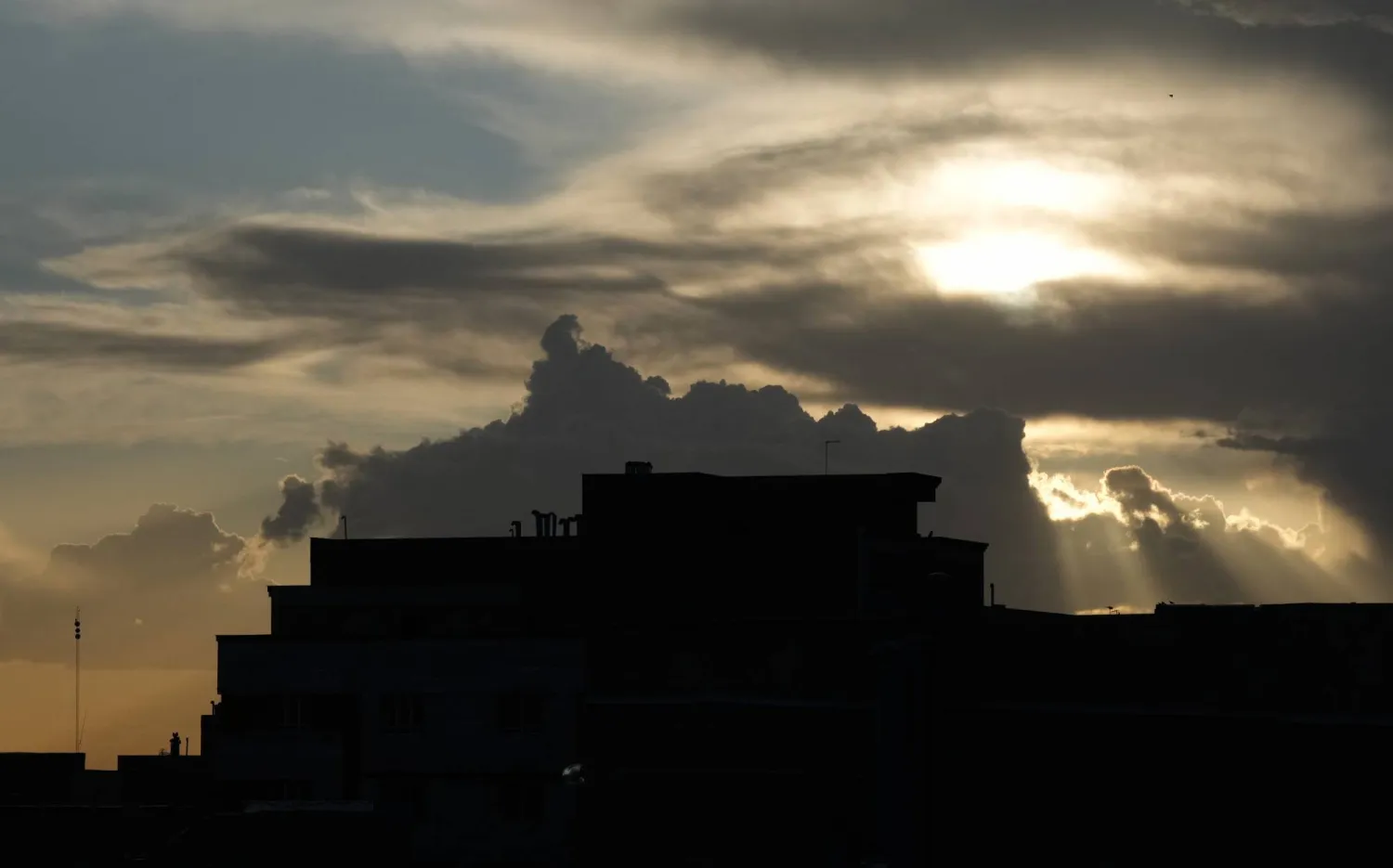 Residential buildings are silhouetted as rays of sunlight shine through clouds in Tehran, Iran, Sunday, April 5, 2026. (AP Photo/Vahid Salemi)