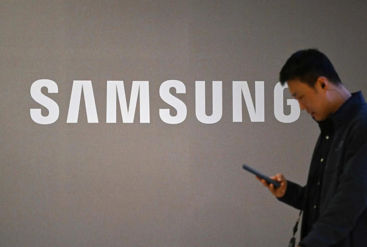 يمر رجل بجوار شعار «سامسونغ» المعروض على مبنى الشركة في سوتشو - سيول (أ.ف.ب)