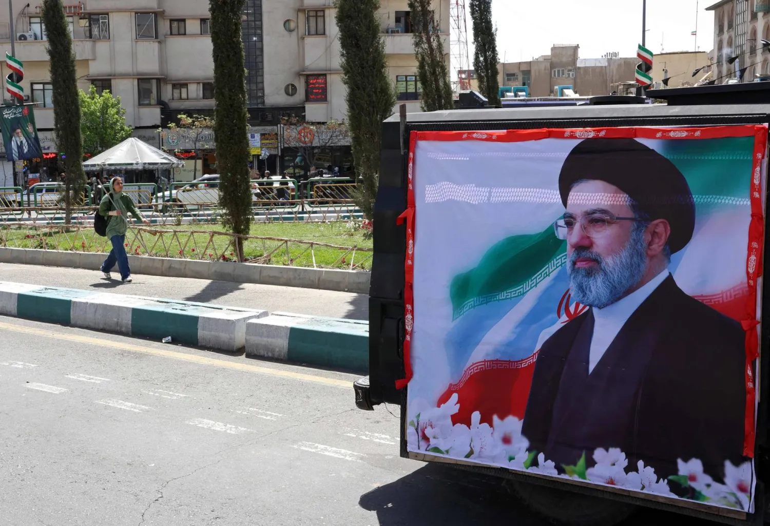 A woman walks past a banner depicting Iran's new supreme leader Mojtaba Khamenei, along a street in Tehran on April 5, 2026.  (Photo by AFP)