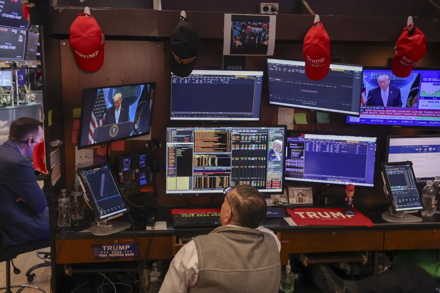 متداول في قاعة بورصة نيويورك بينما تُظهر الشاشة خطاب الرئيس دونالد ترمب خلال مؤتمر صحافي حول الحرب مع إيران (إ.ب.أ)