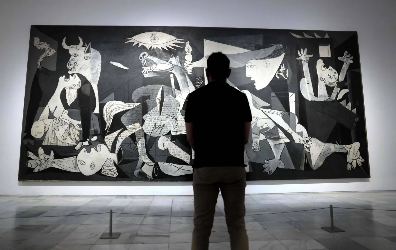 A visitor looks at Spanish painter Pablo Picasso's master piece "Guernica" during a press conference presenting the "Year of Picasso" events, marking the 50th anniversary of the painter's death, at the Reina Sofia museum in Madrid, on September 12, 2022. (Thomas Coex/ AFP)