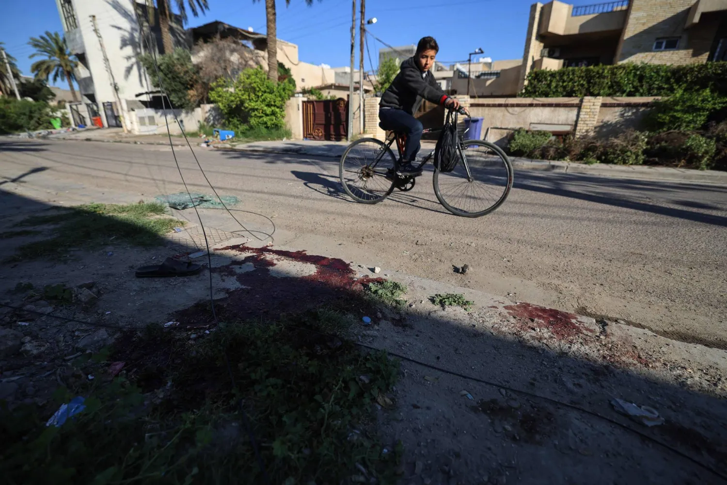 صبيّ يقود دراجة هوائية ويمرّ بجانب بقع دم في موقعٍ تعرّض فيه منزل لدمارٍ جزئي نتيجة مقذوف سقط فجر 8 أبريل 2026 (أ.ف.ب)