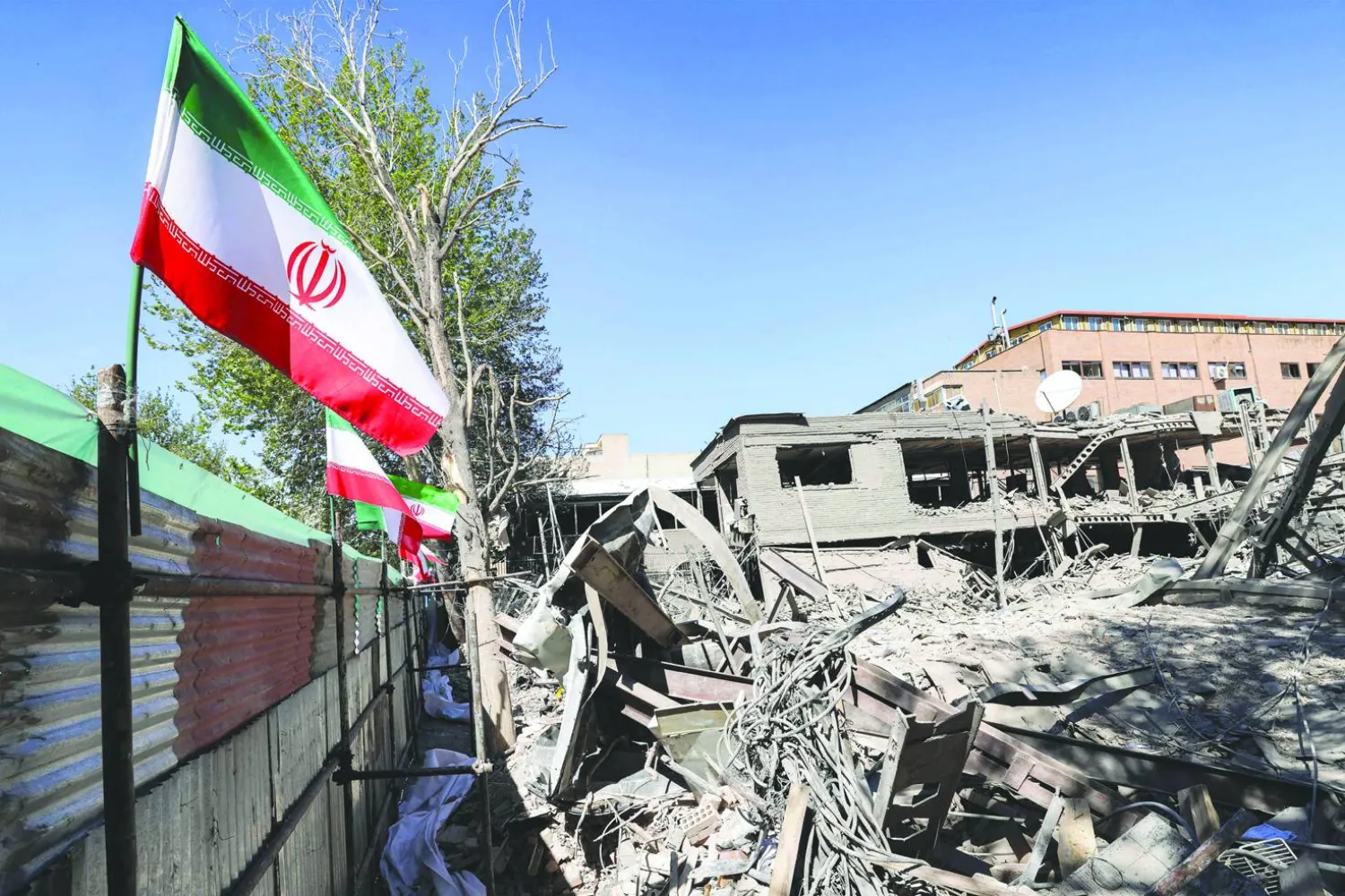 An Iranian national flag is placed by the rubble of a collapsed building following strikes at Sharif University of Technology in Tehran on April 7, 2026. (Photo by ATTA KENARE / AFP) / 