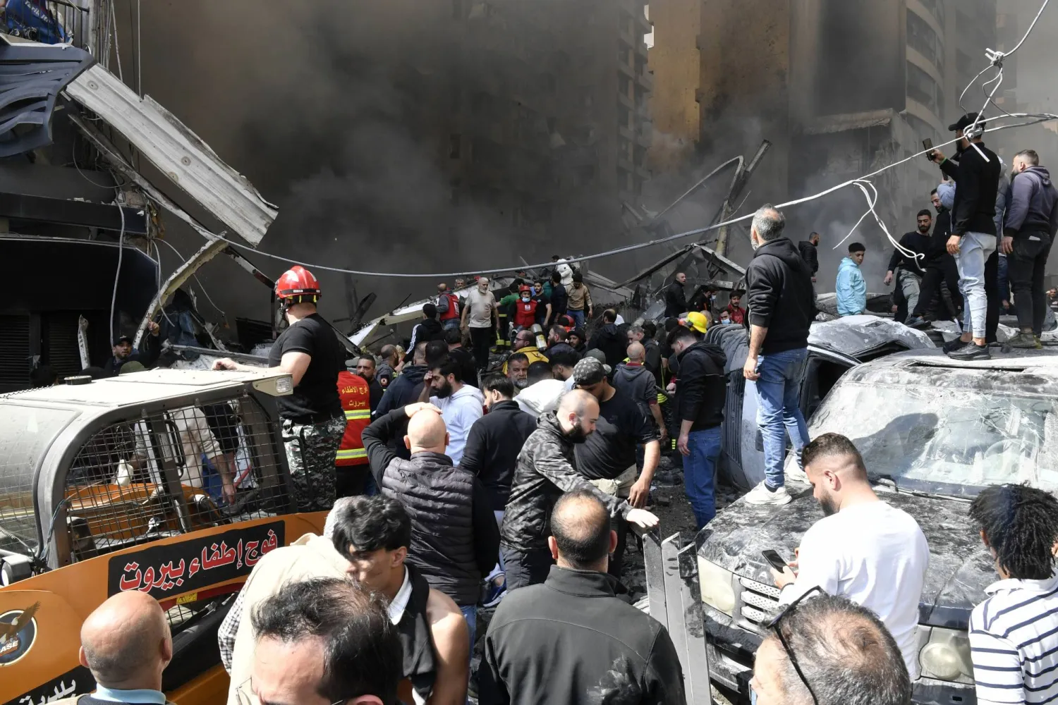 مواطنون يتجمعون أمام مبنى استهدف بغارة إسرائيلية في منطقة كورنيش المزرعة في بيروت (إ.ب.أ) 