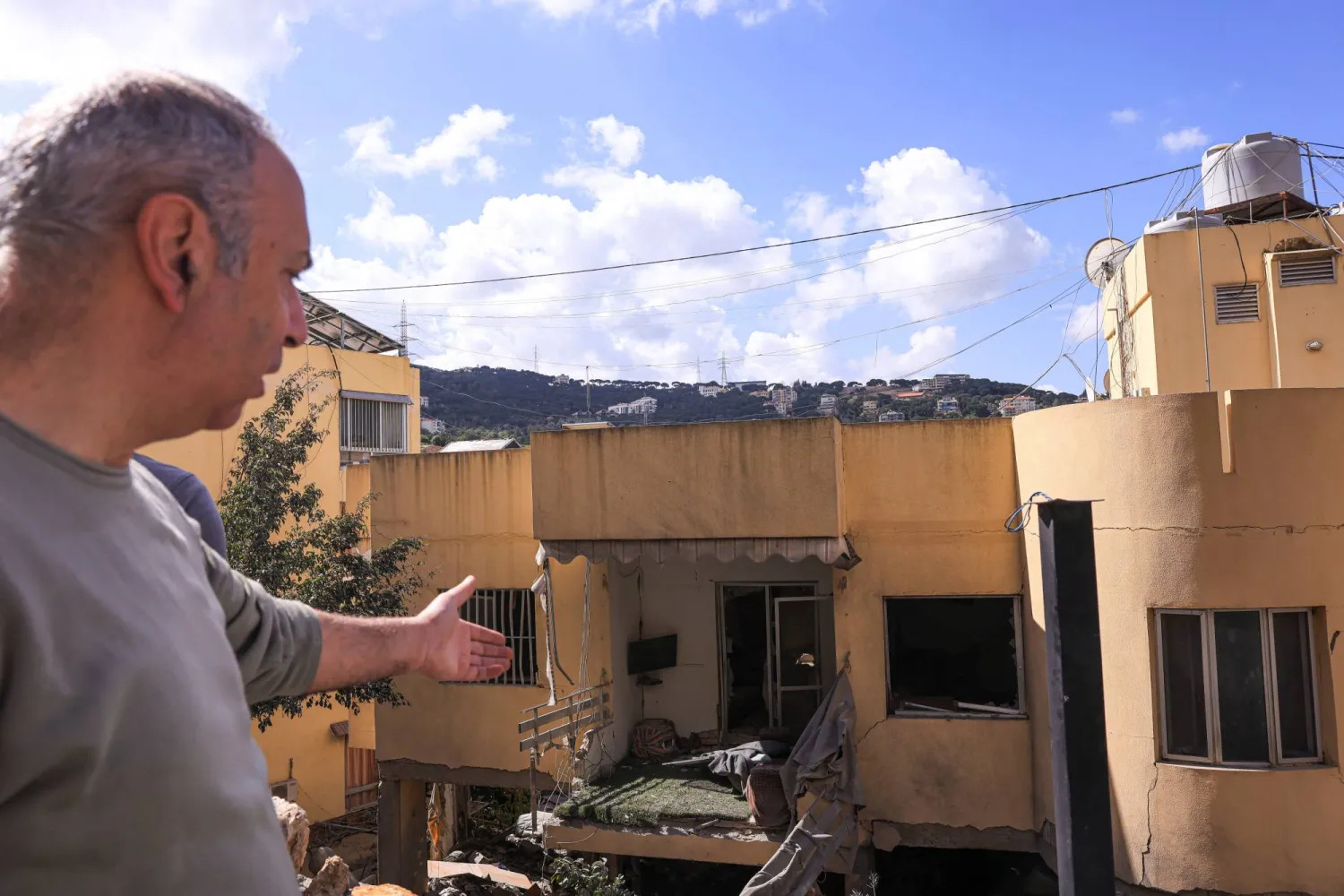 أحد السكان المحليين يشير إلى الأضرار التي لحقت بمبنى سكني تعرض لغارة إسرائيلية في عين سعادة بلبنان (رويترز) 