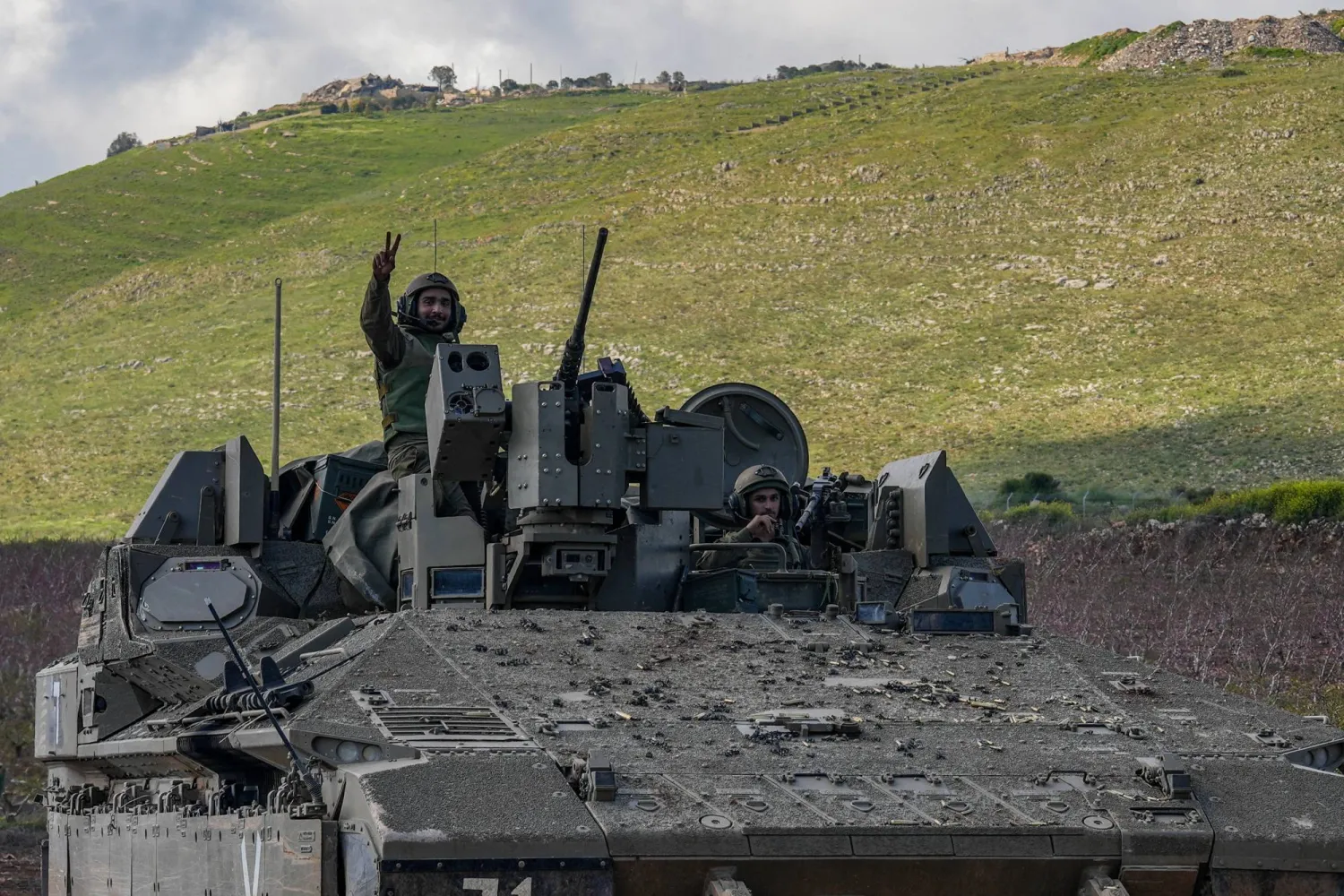 An Israeli soldier gestures from an Israeli armored personnel carrier (APC), as they leave southern Lebanon and enter Israel, as seen from the Israeli side of the border, April 8, 2026. REUTERS/Ayal Margolin  