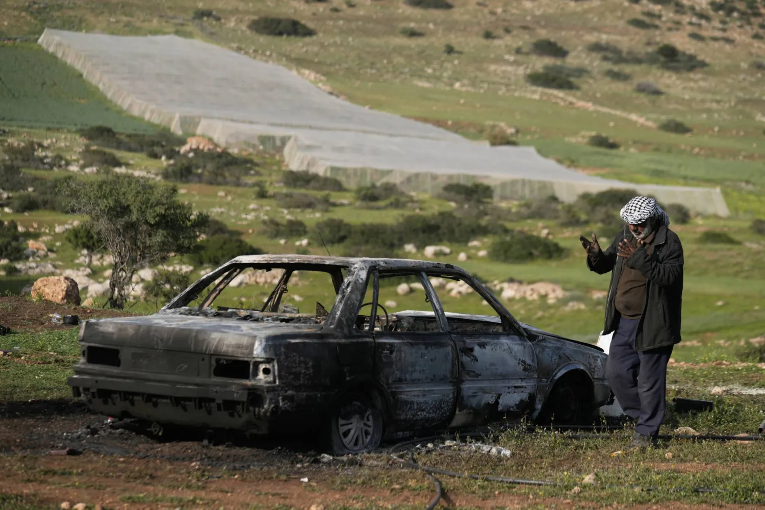 A resident inspects a car that, according to the Palestine Red Crescent, was torched by Israeli settlers in the West Bank village of Tayasir, near Tubas, Tuesday, March 31, 2026. (AP Photo/Majdi Mohammed)