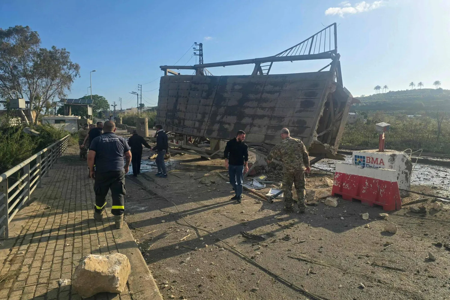 عناصر من الدفاع المدني يتفقدون الأضرار الناتجة عن قصف إسرائيلي استهدف جسر القاسمية فوق نهر الليطاني بجنوب لبنان (أ.ف.ب)
