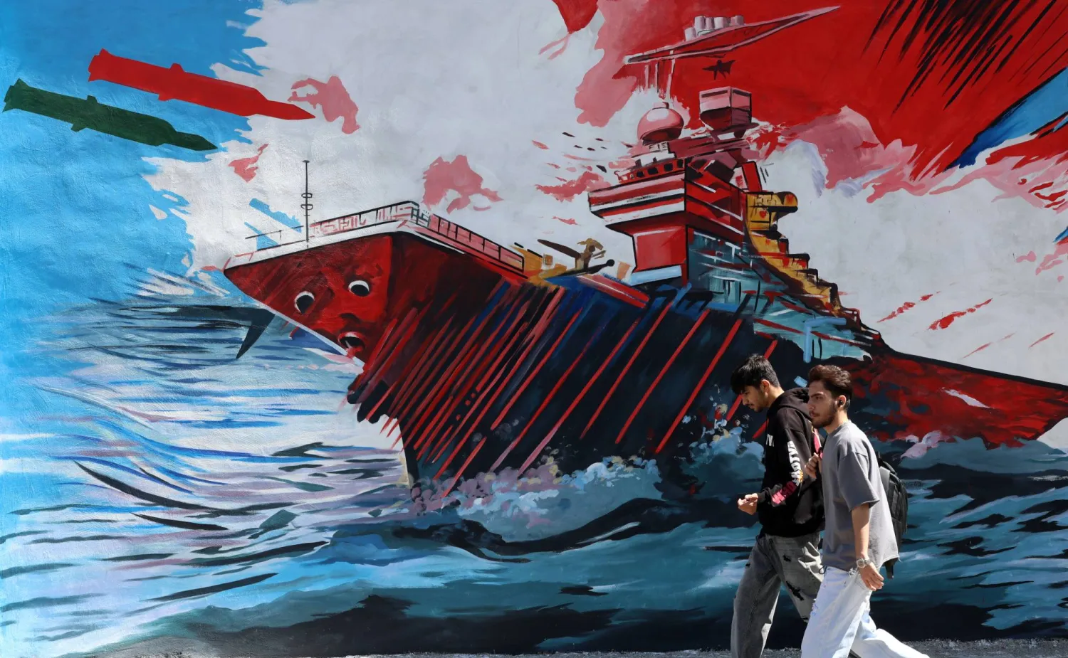 رجلان يمران أمام لوحة جدارية مناهضة للولايات المتحدة وإسرائيل في طهران (إ.ب.أ)