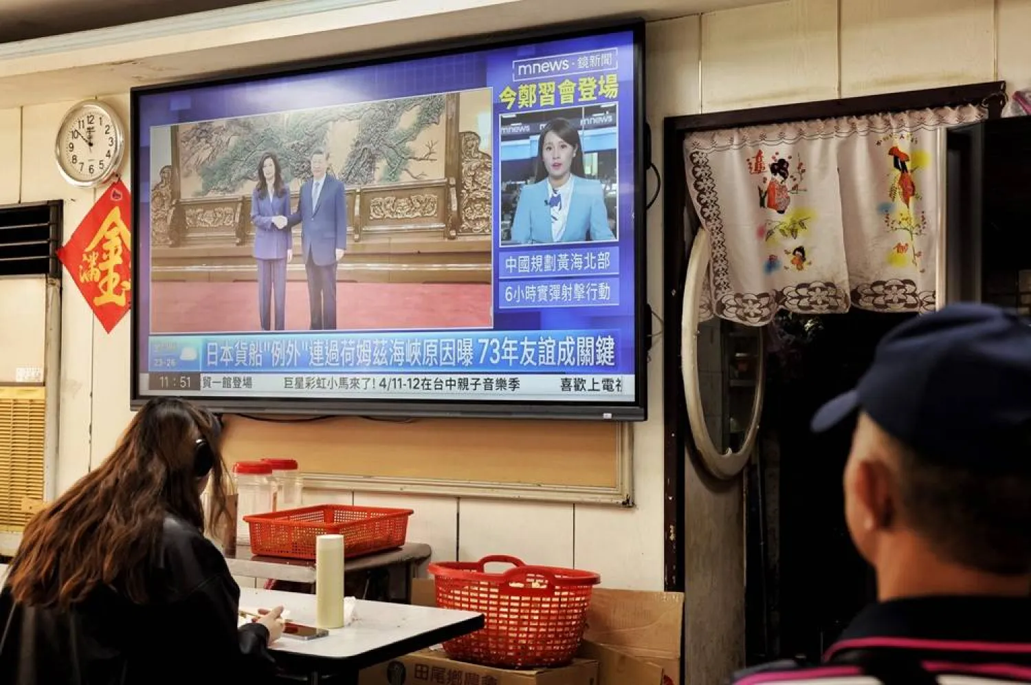 A television shows the meeting between Kuomintang (KMT) chairwoman Cheng Li-wun and Chinese President Xi Jinping in Beijing, at a restaurant in Taipei on April 10, 2026. (AFP) 